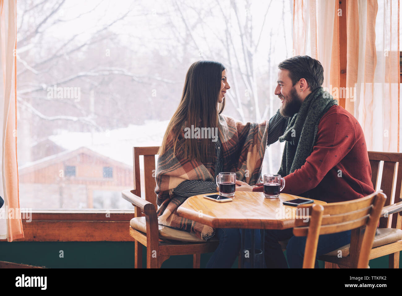 Heureux couple assis par fenêtre dans cafe Banque D'Images