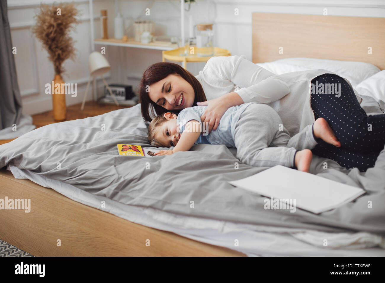 Happy mother lying with baby boy in bed at home Banque D'Images