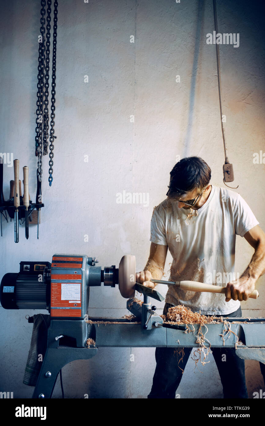 Carpenter holding ciseau tout en façonnant bol en bois en atelier Banque D'Images