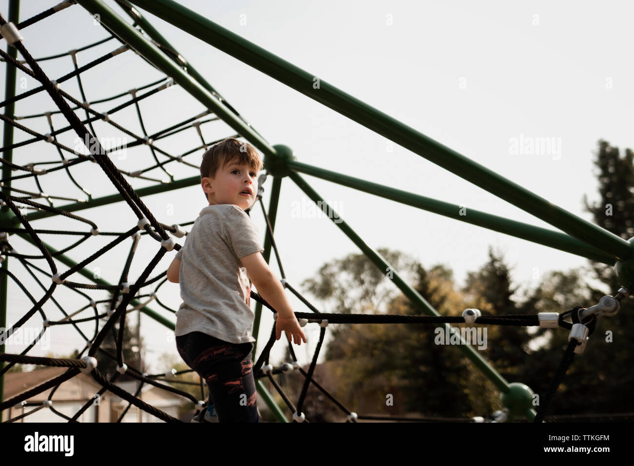 Jeune garçon l'ascension d'une araignée au parc Banque D'Images