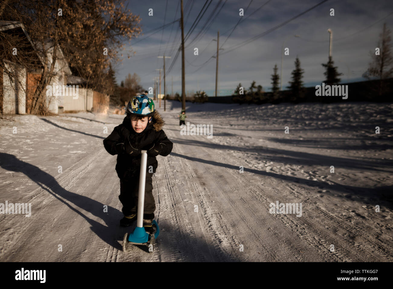 Boy riding scooter dans la ruelle vers le bas d'hiver Banque D'Images