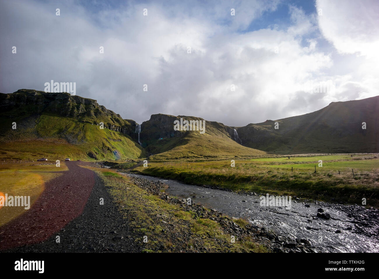 Vue panoramique des montagnes, au milieu du flux par champ contre ciel nuageux Banque D'Images