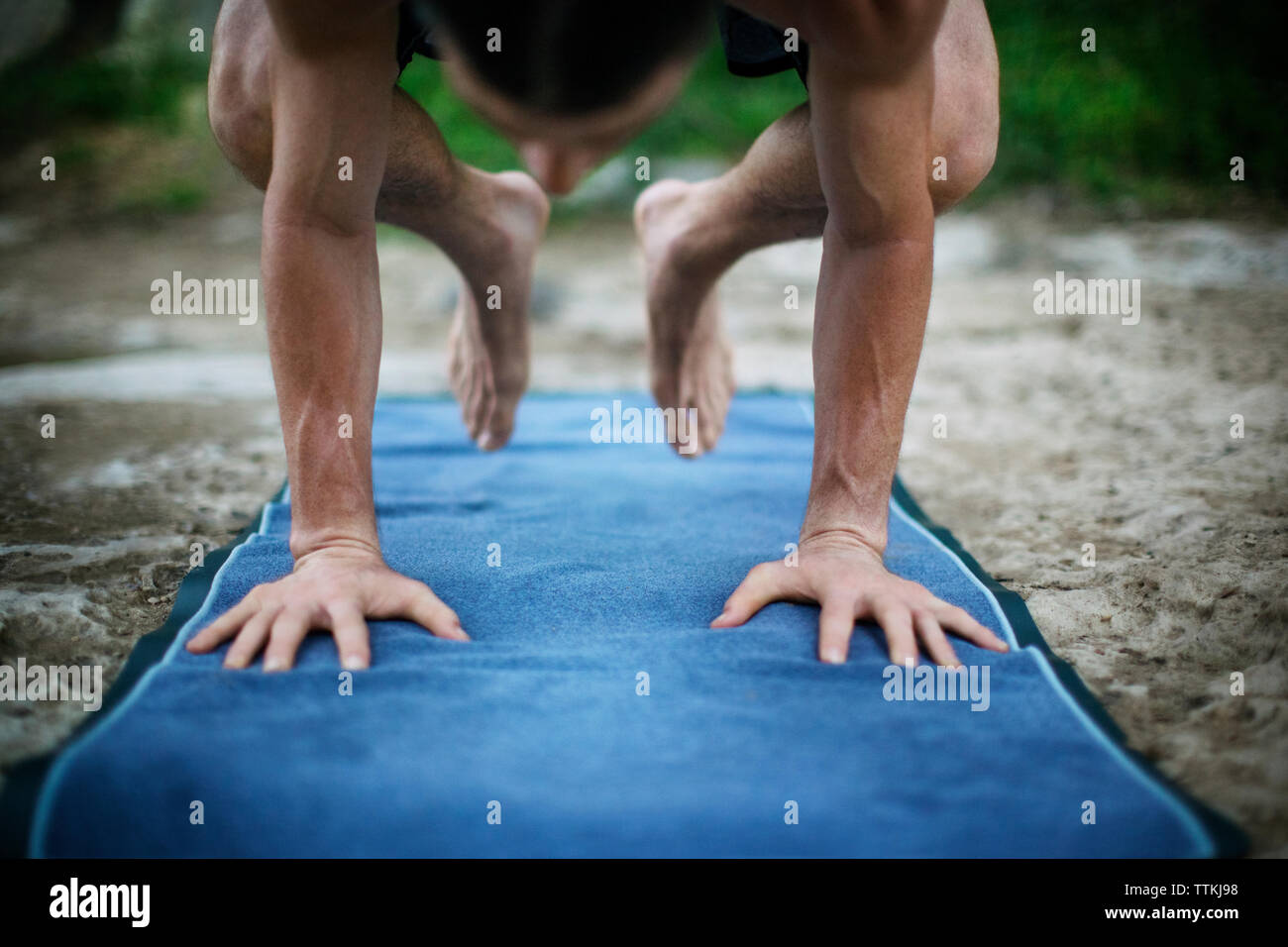 Man practicing yoga in posture du corbeau on exercise mat Banque D'Images