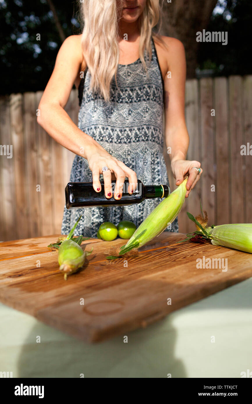 Portrait woman pouring olive oil sur le maïs Banque D'Images