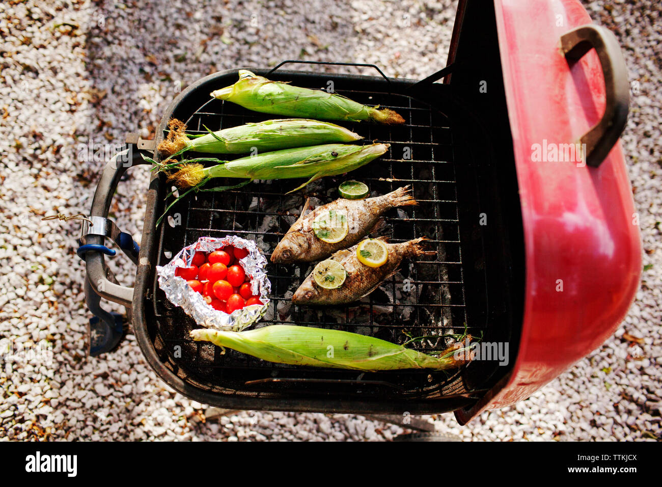 Vue aérienne de poissons et de maïs avec des tomates cerise sur le gril du barbecue Banque D'Images