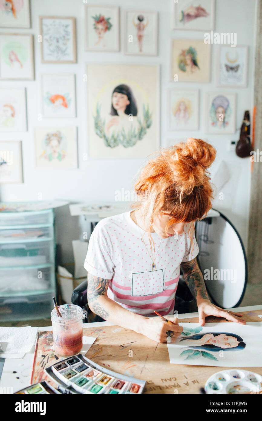Peinture artiste féminine tout en se tenant à la table en studio Banque D'Images