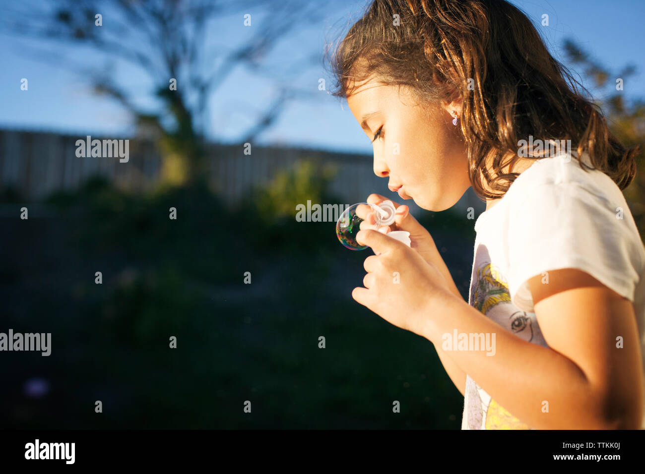 Close-up of girl blowing bubble avec baguette sur sunny day Banque D'Images