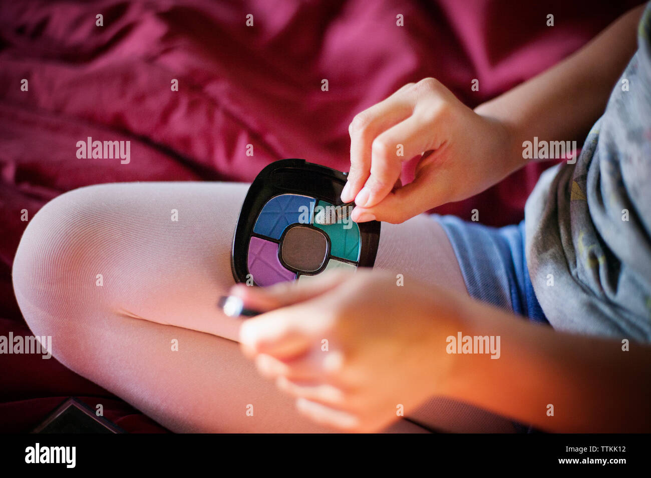 Portrait of Girl holding makeup on bed Banque D'Images