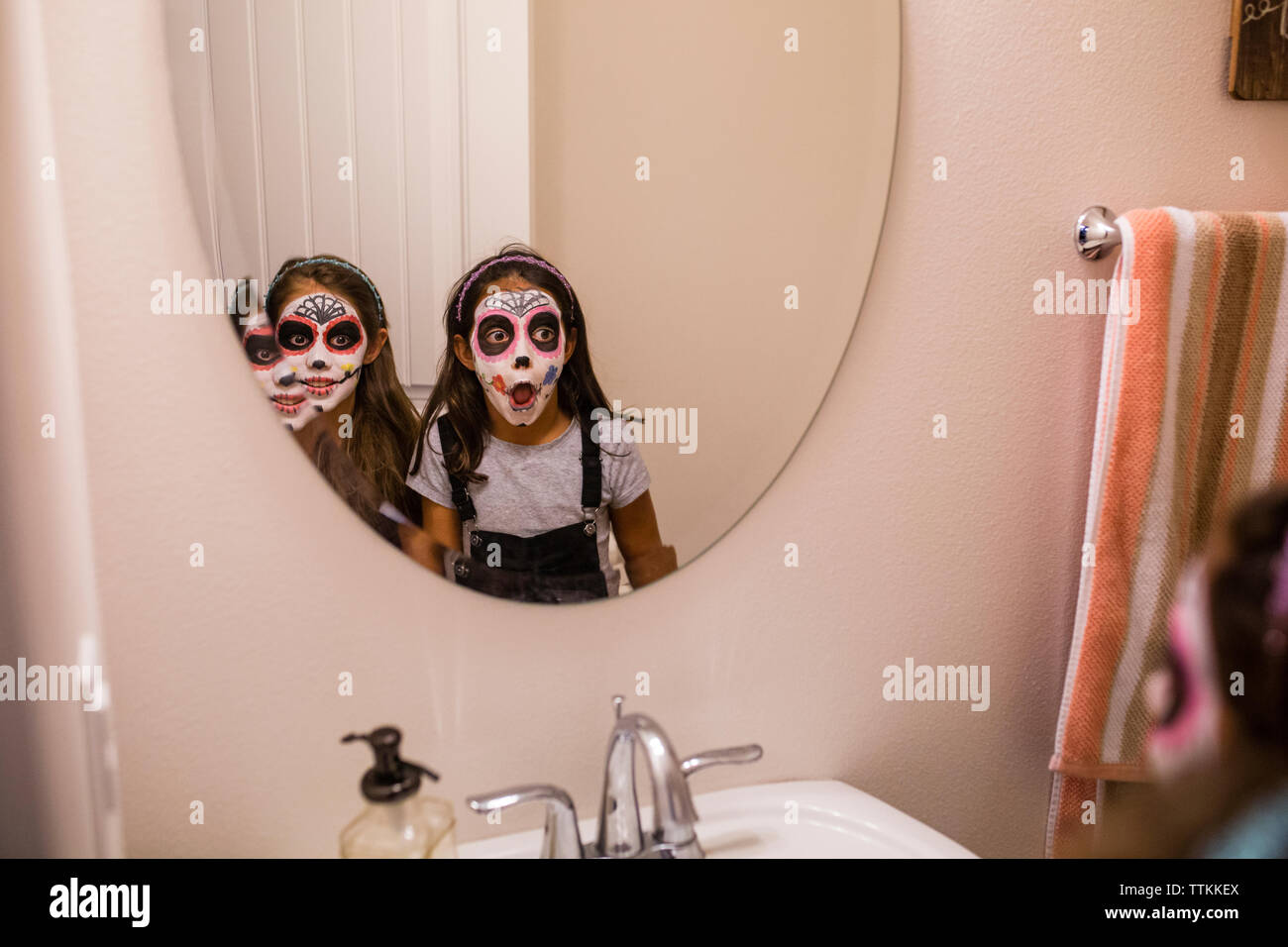 Les sœurs avec la peinture pour le visage à la recherche de miroir dans Banque D'Images