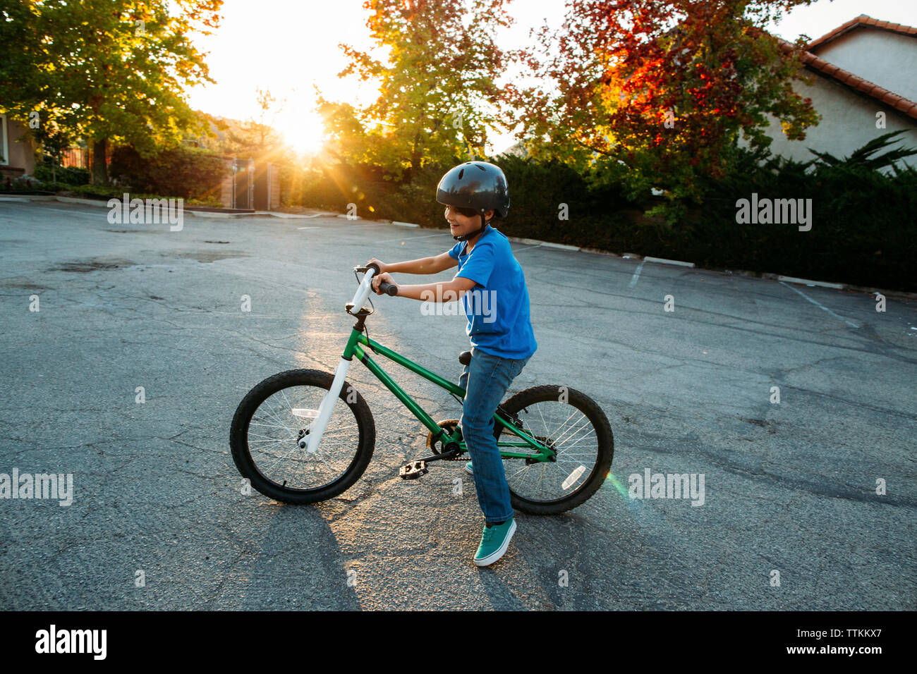 Boy wearing casque de vélo tout en vélo pendant le coucher du soleil Banque D'Images