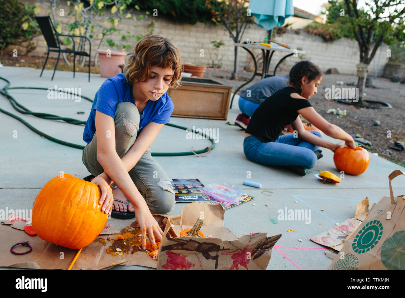 Trois enfants découper les citrouilles à l'extérieur Banque D'Images