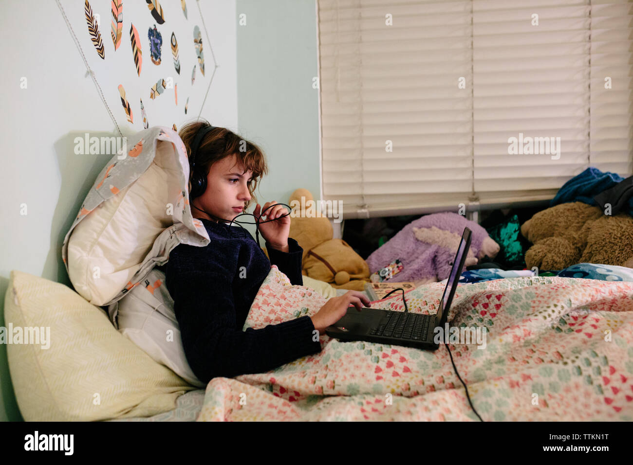 Girl in bed with laptop et écouteurs Banque D'Images