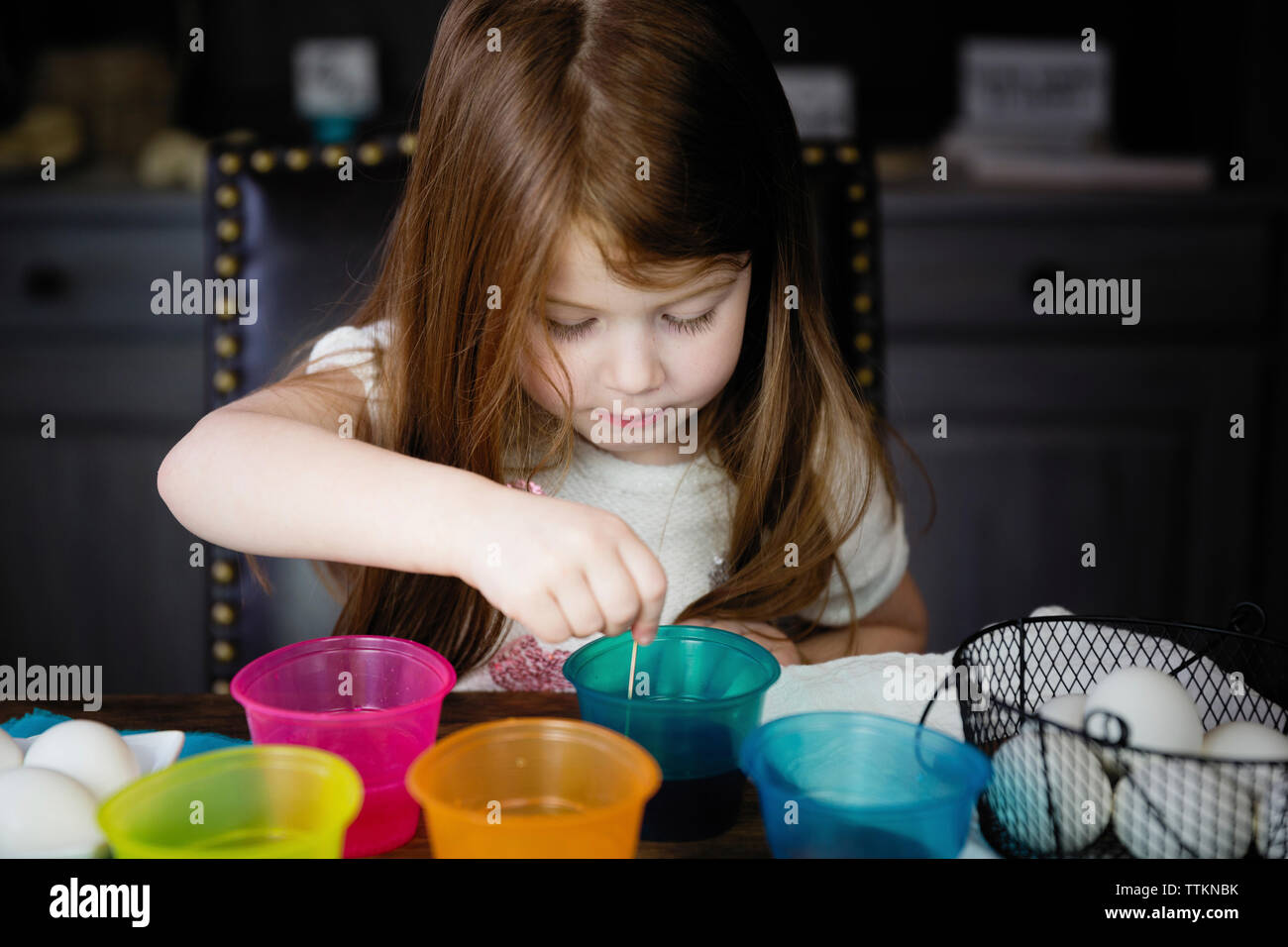 Jolie fille coloriant les œufs de pâques sur la table à la maison Banque D'Images