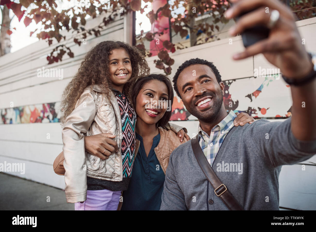 En famille on mobile phone at selfies trottoir Banque D'Images
