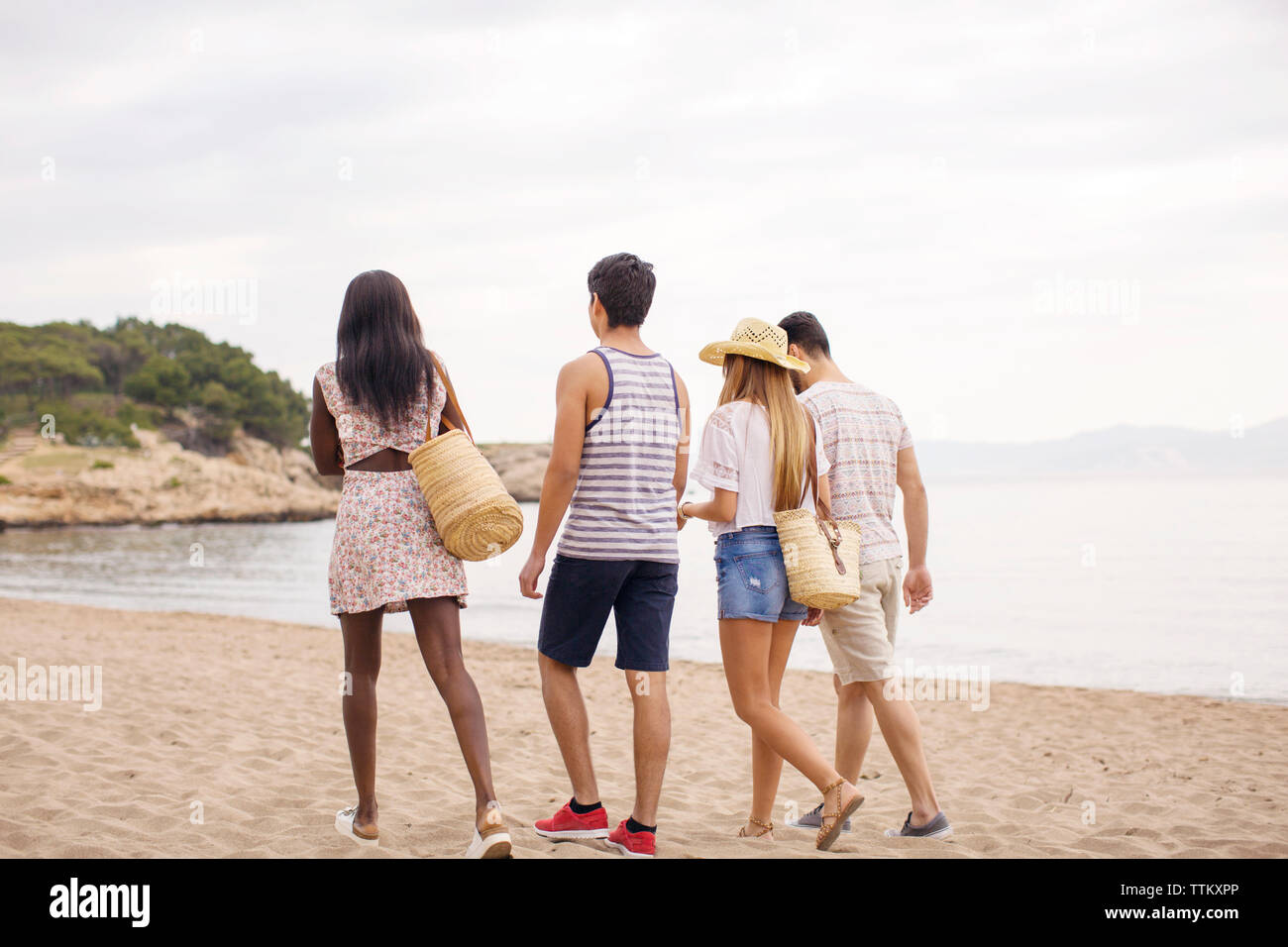 Vue arrière du multi-ethnic friends walking on beach Banque D'Images