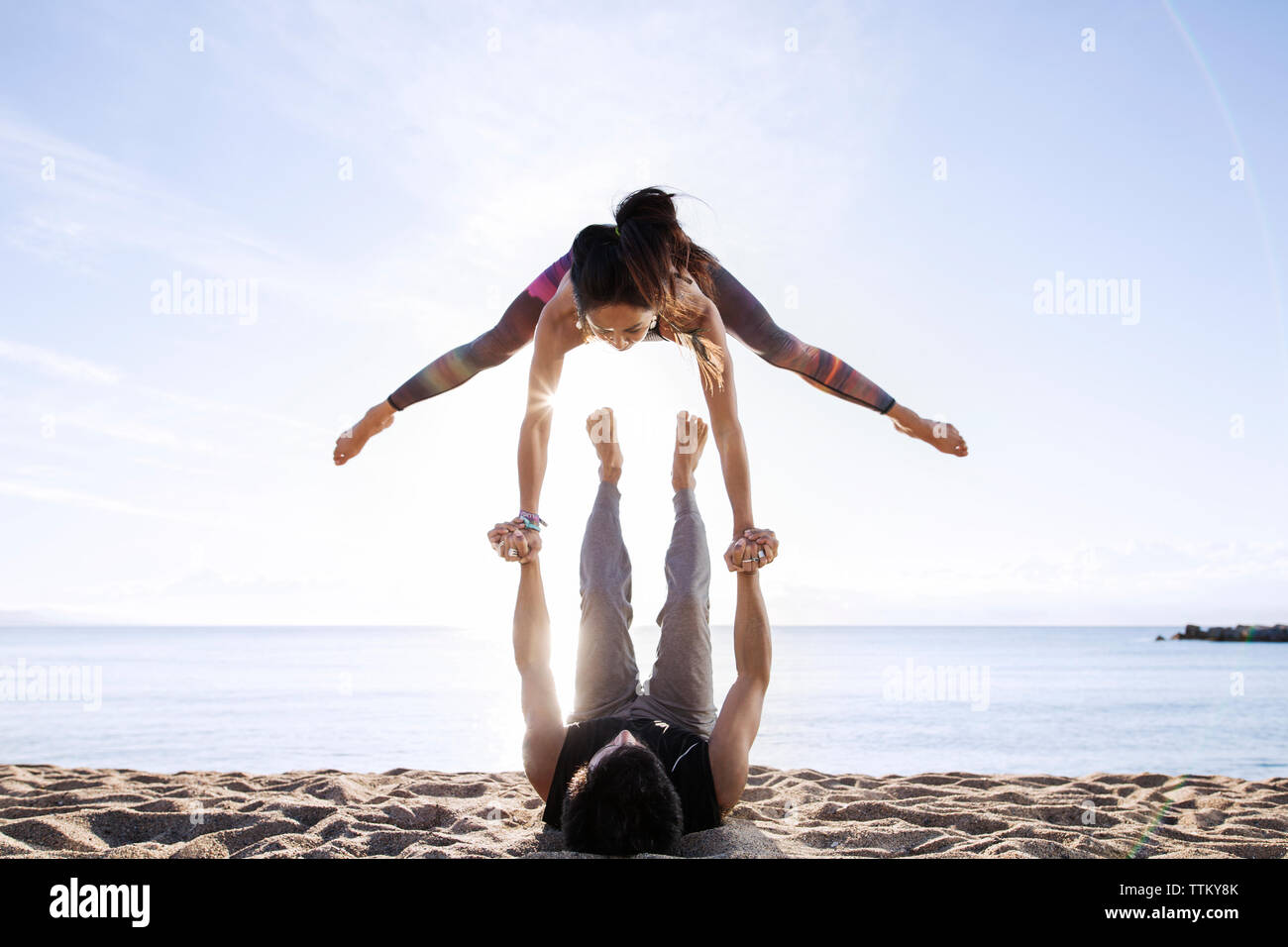 Homme Femme de levage tout en faisant du yoga sur la plage en été Banque D'Images