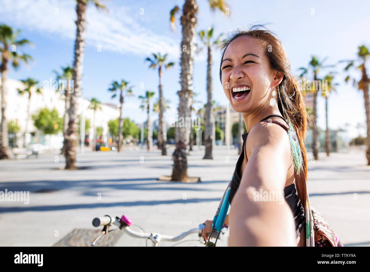 Portrait of cheerful woman riding bicycle sur route au cours de l'été Banque D'Images