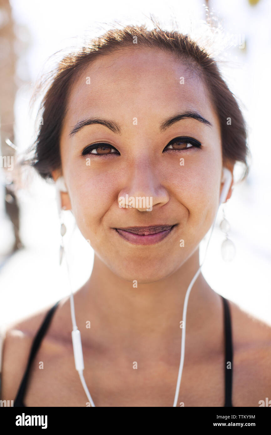 Close-up portrait of smiling young woman wearing earphones Banque D'Images