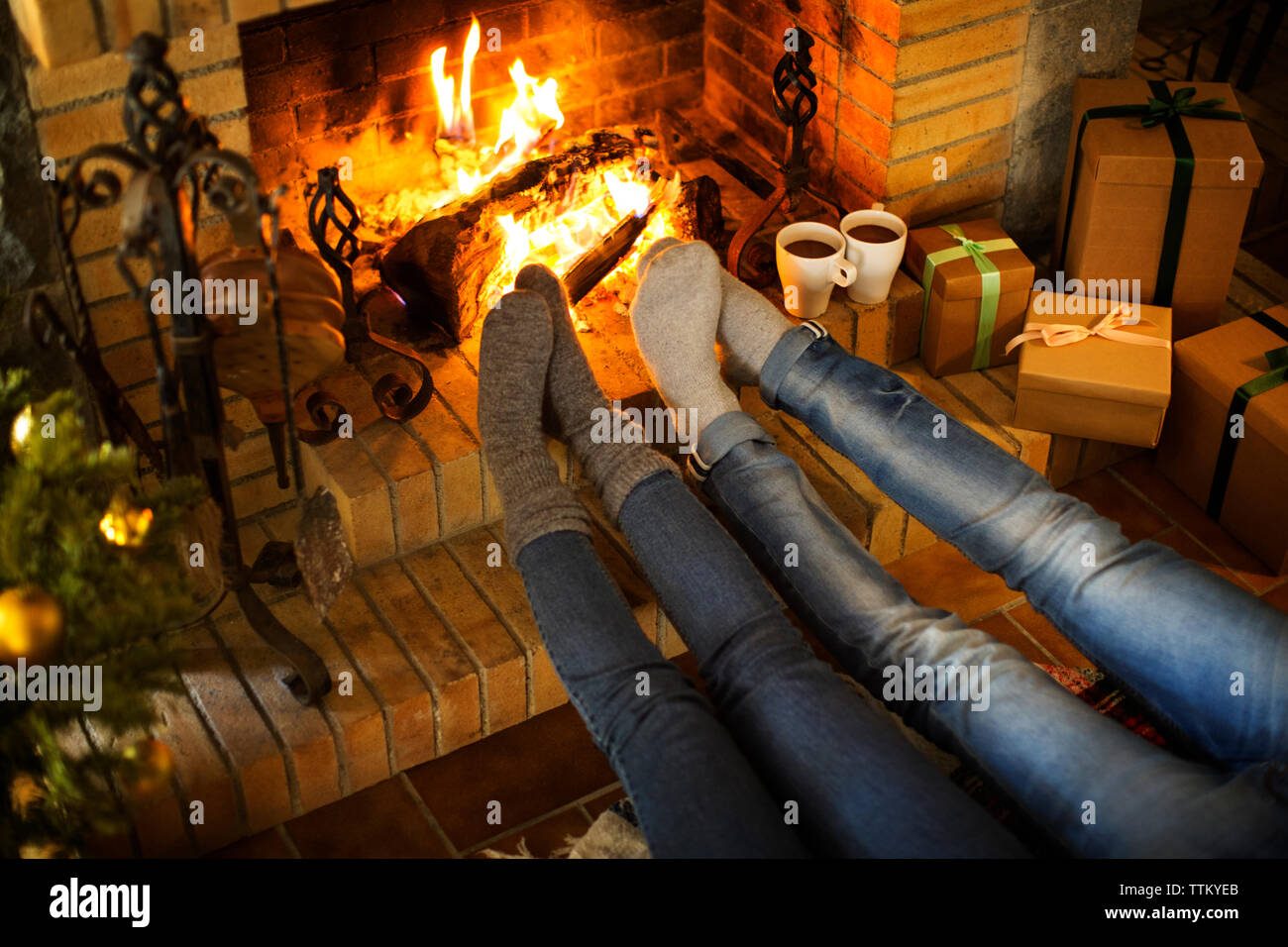 Section basse de couple reposant par cheminée et cadeaux de noël à la maison Banque D'Images