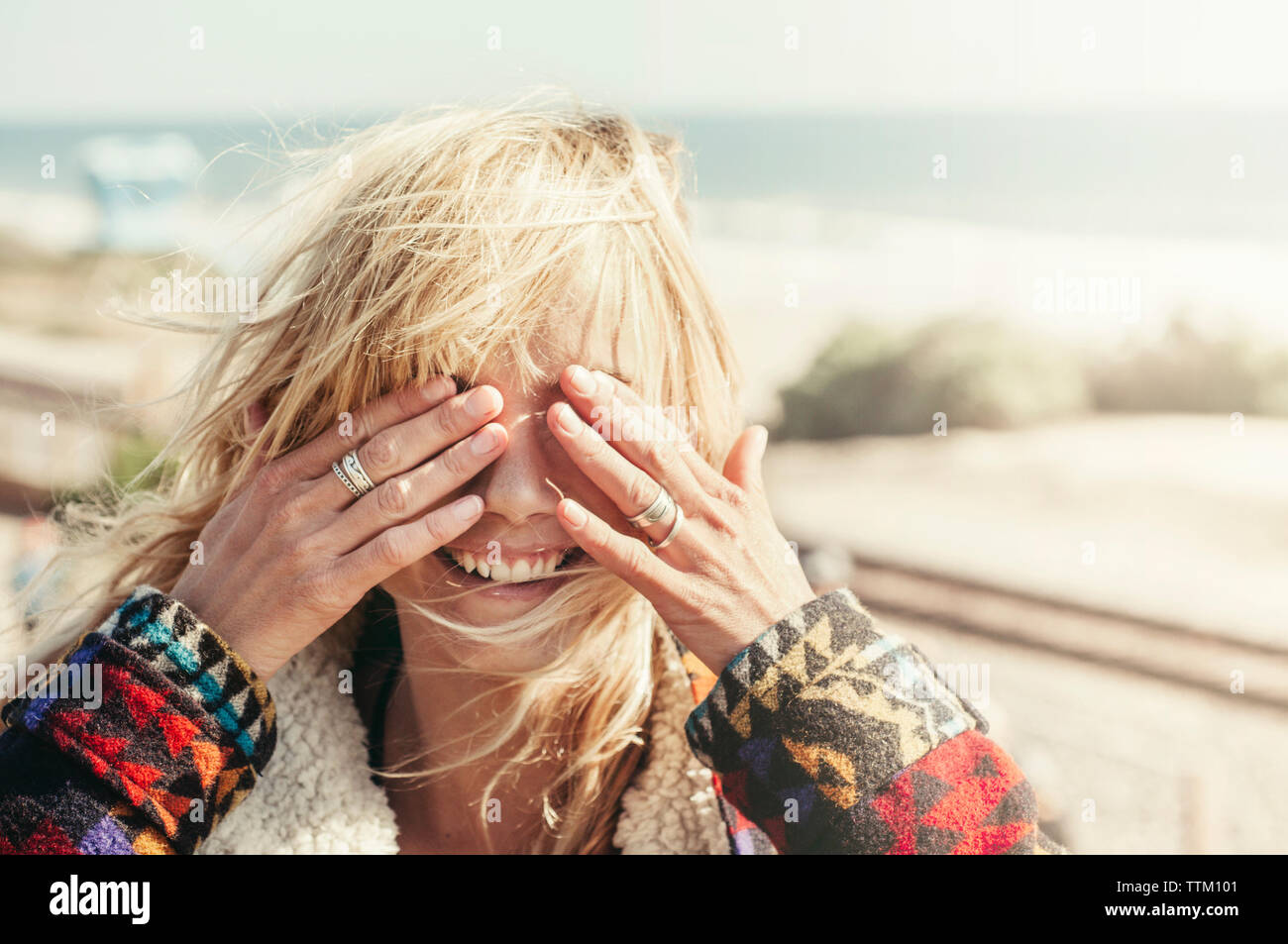 Happy young woman covering eyes on beach Banque D'Images