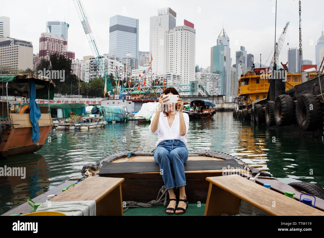 Photographier une femme en position assise sur le bateau dans la ville Banque D'Images