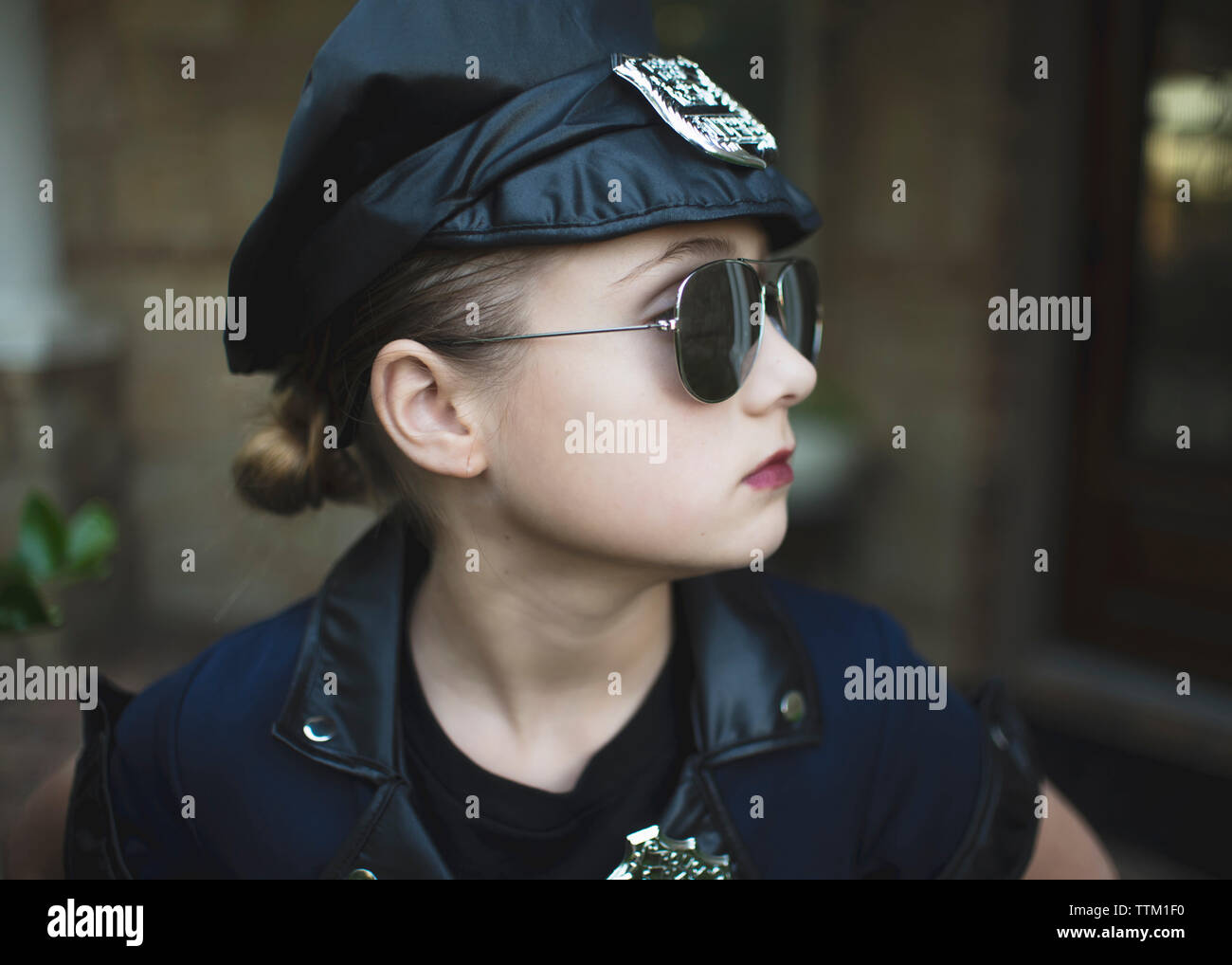 Close-up of certain fille en costume de police portant des lunettes de soleil en position debout contre Chambre au cours de l'Halloween Banque D'Images