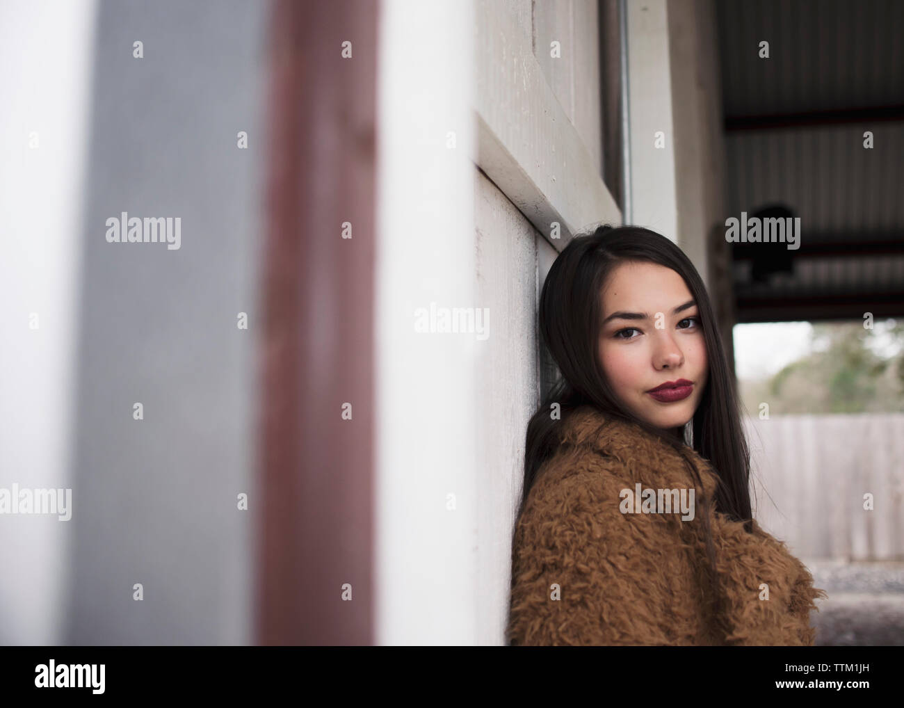 Fille brune appuyée contre un mur. Banque D'Images