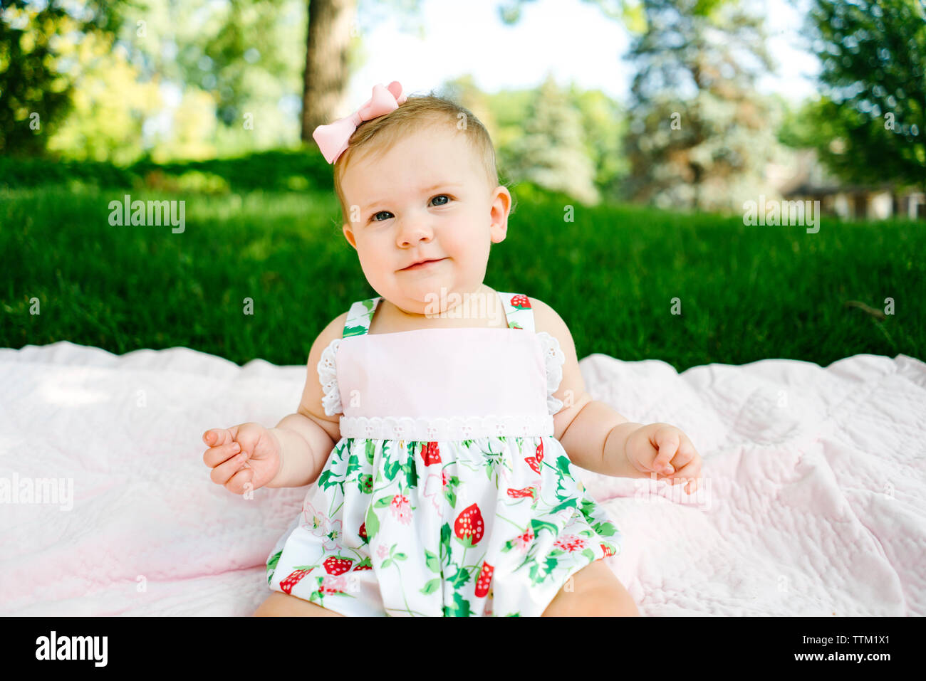Un closeup portrait of a baby girl sitting sur une couverture à l'extérieur Banque D'Images