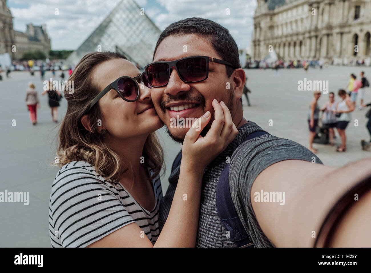 Portrait de petite amie kissing boyfriend contre Musée du Louvre en ville Banque D'Images