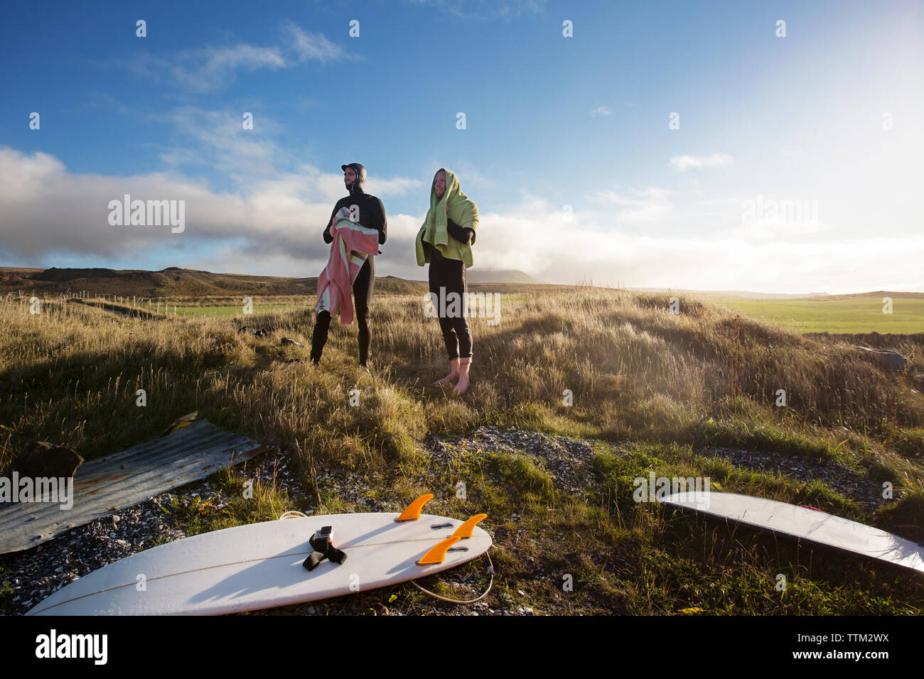 Les surfeurs à l'écart en se tenant sur le terrain herbeux against sky Banque D'Images