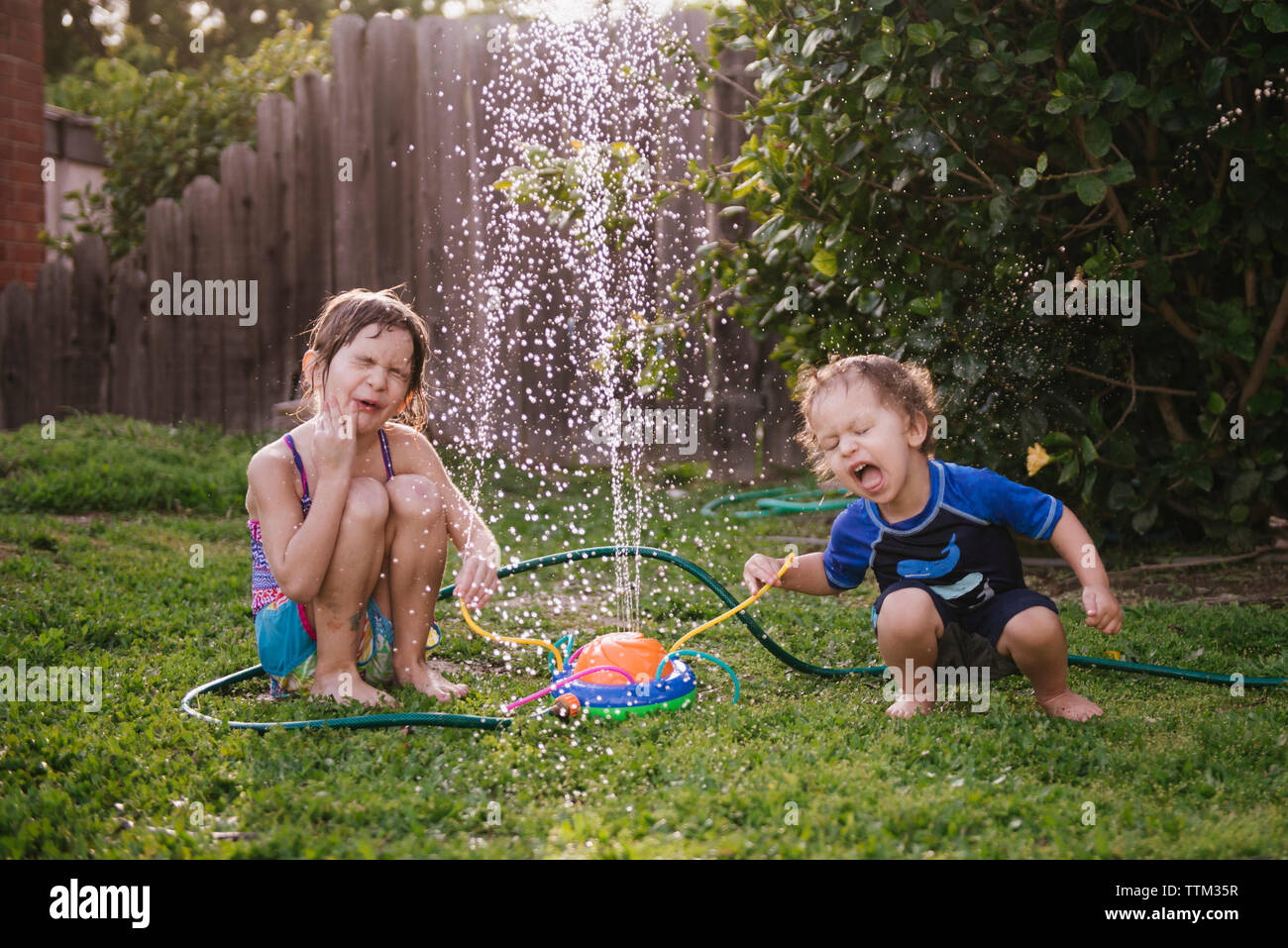 Siblings playing par fontaine dans une cour Banque D'Images