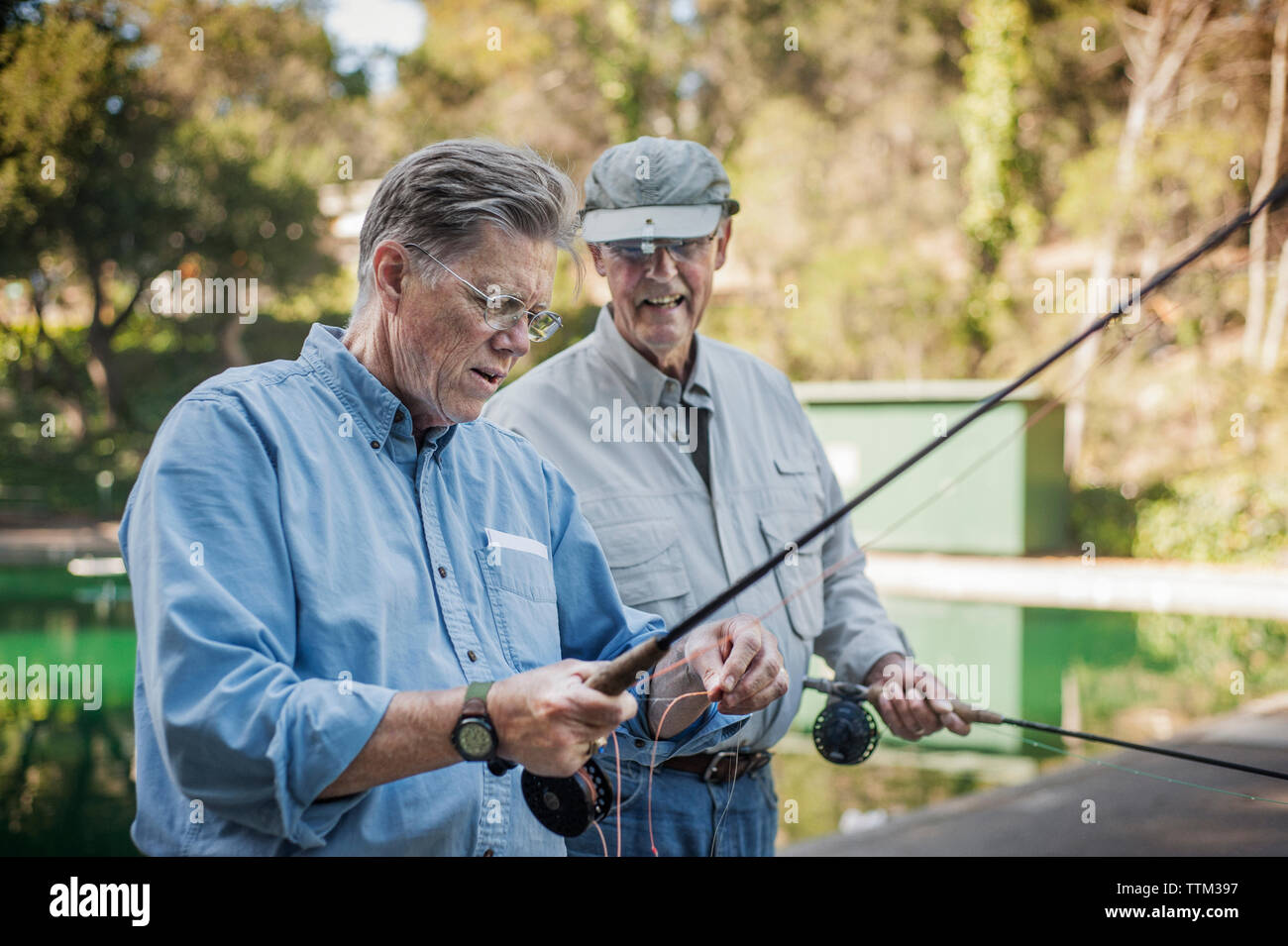 Happy senior male friends holding des cannes à pêche en forêt Banque D'Images