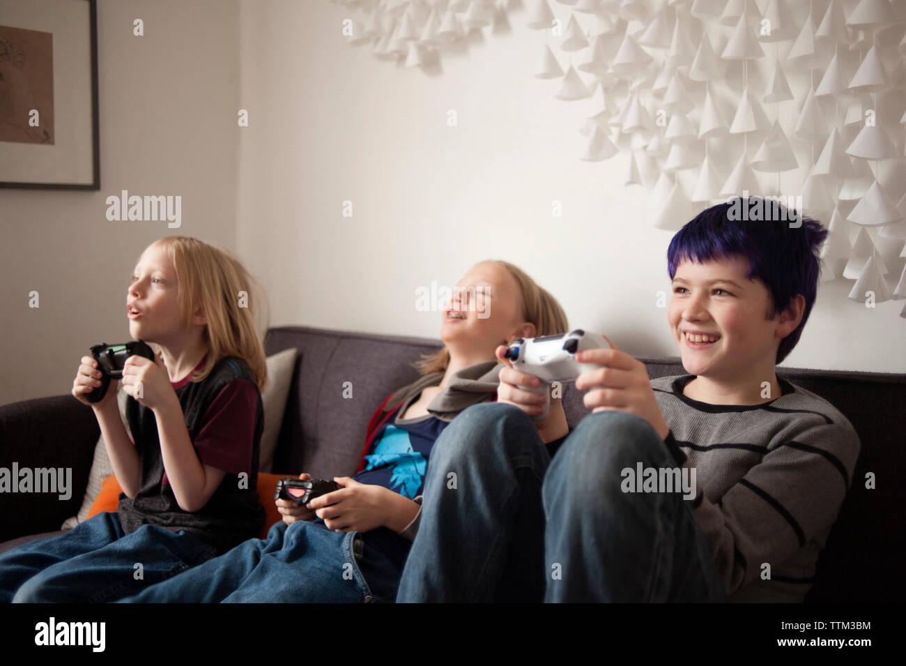 Garçons assis sur un canapé et playing video game Banque D'Images