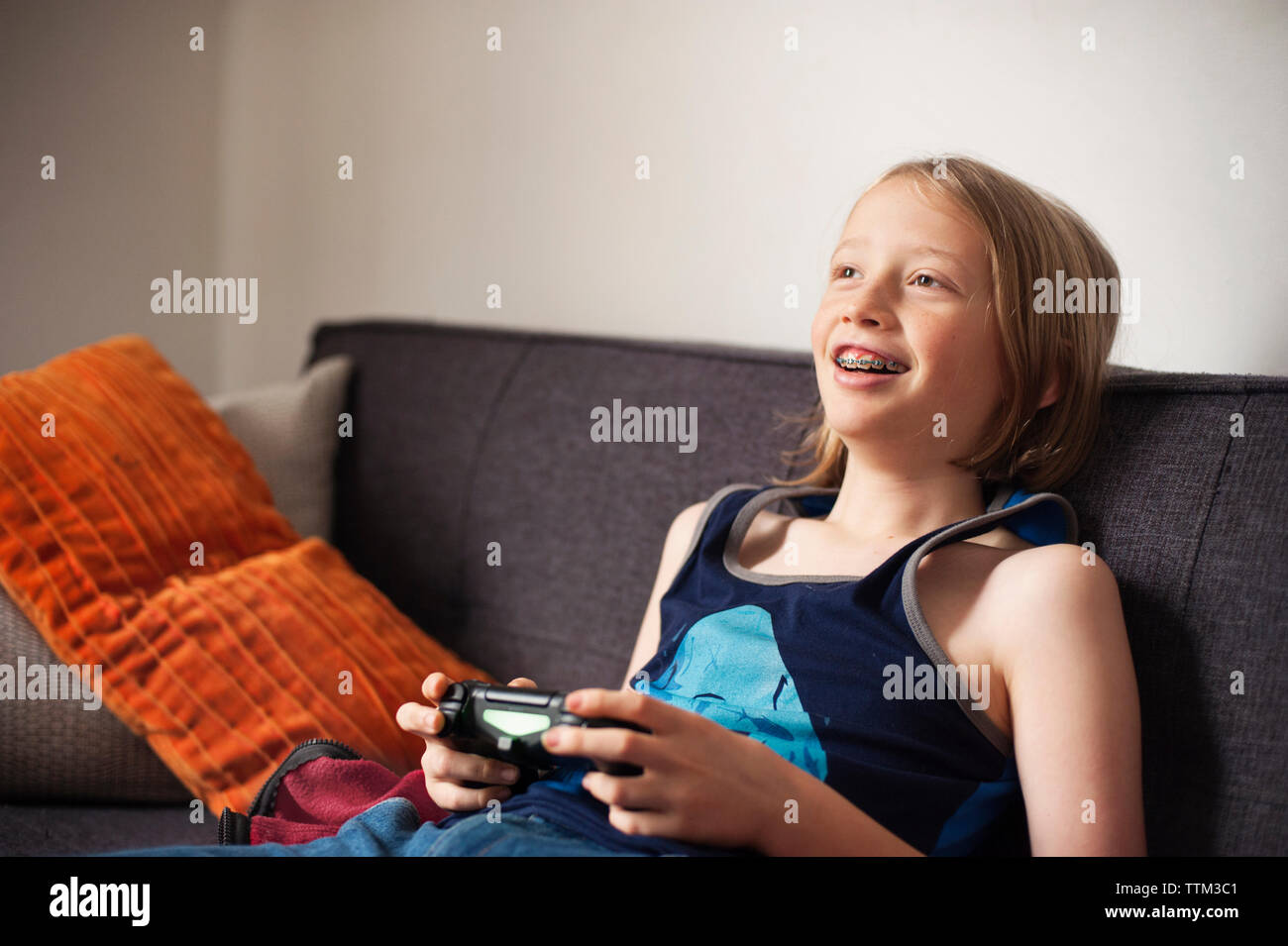 Happy boy sitting on sofa and playing video game Banque D'Images