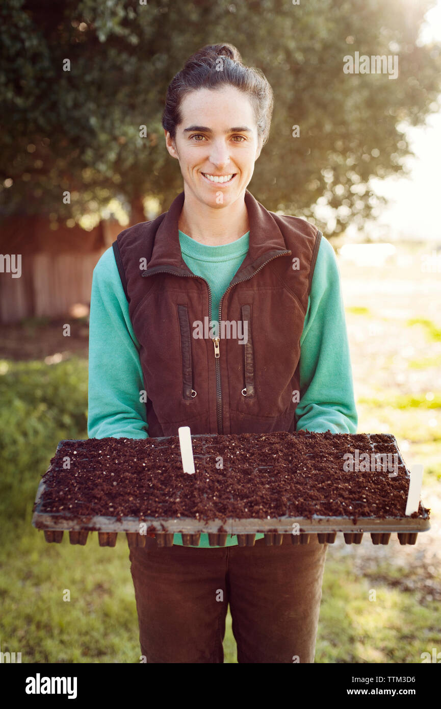 Portrait of happy woman holding bac de semis à la ferme Banque D'Images