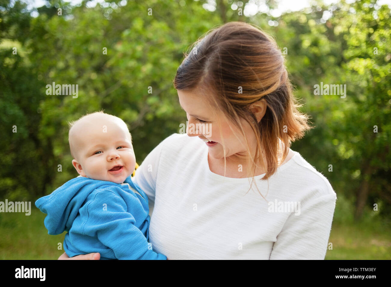 Happy woman carrying baby boy at park Banque D'Images