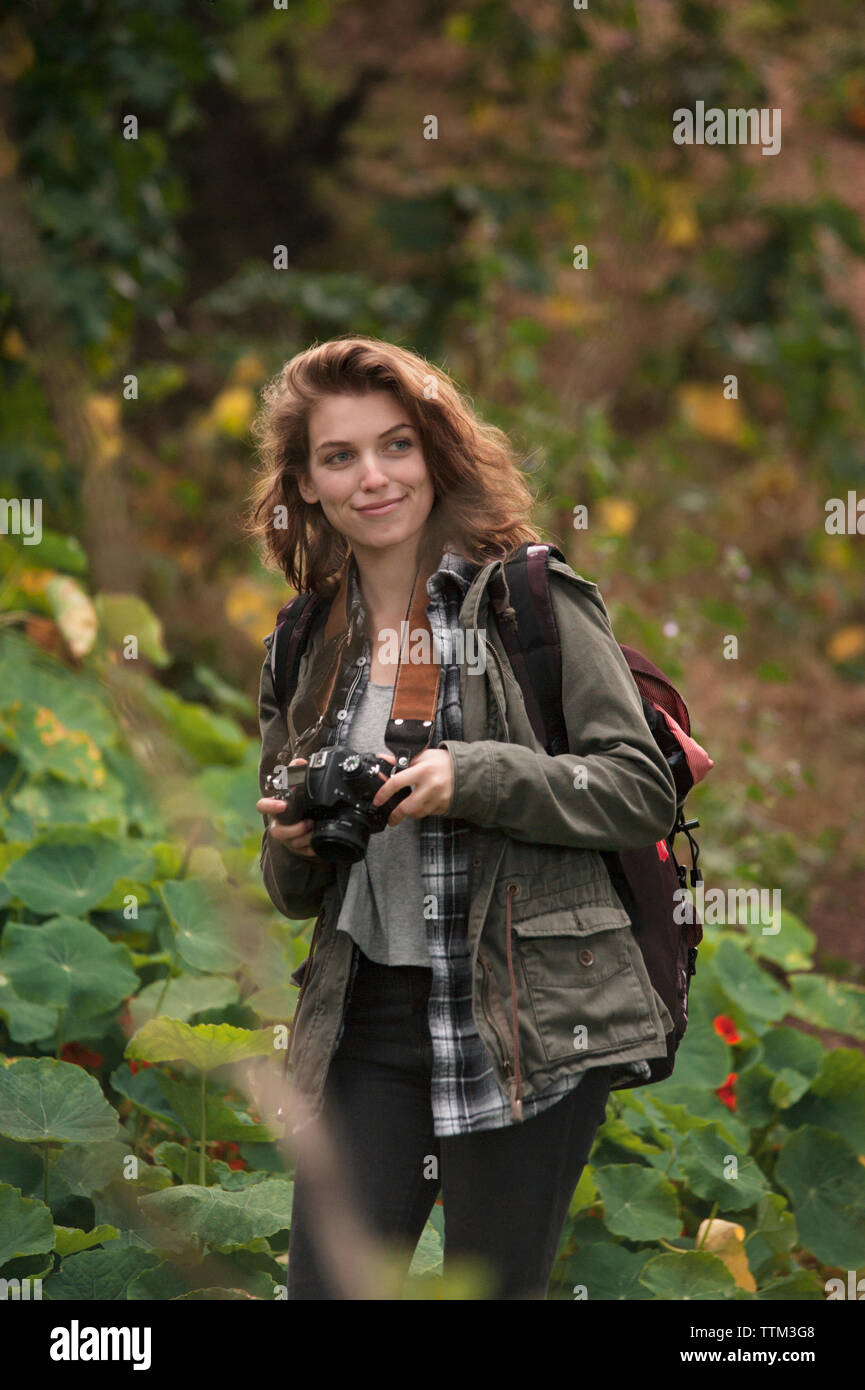 Female hiker holding camera in forest Banque D'Images