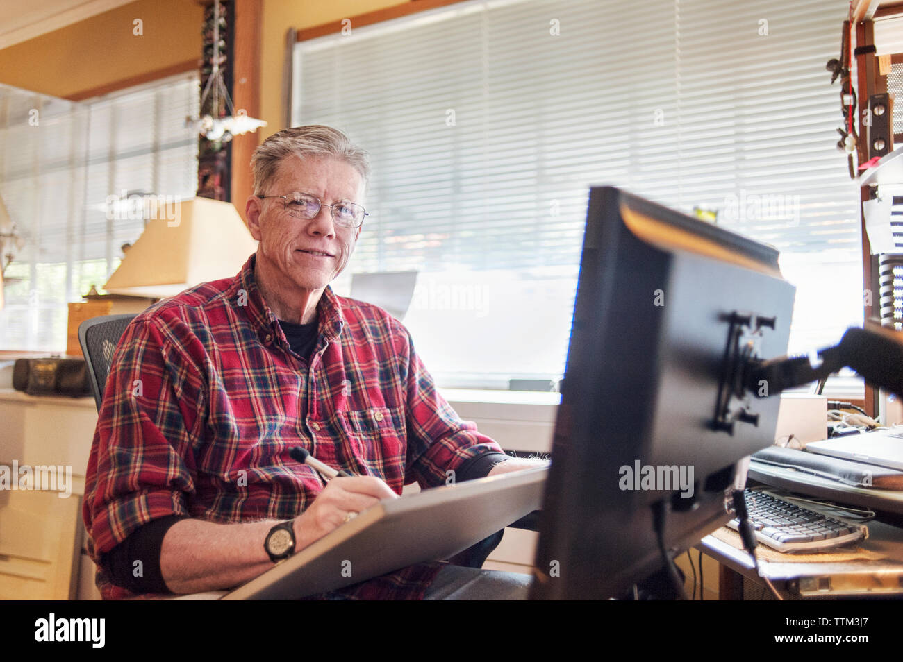 Portrait of senior man à l'aide de tablette graphique à la maison Banque D'Images