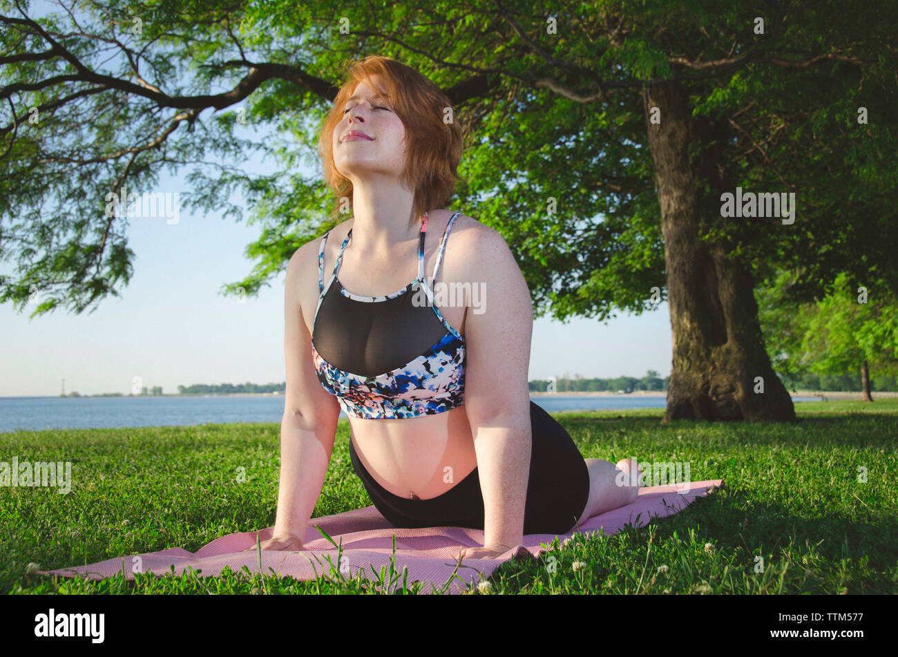 Low angle view of woman on exercise mat pose cobra at park Banque D'Images