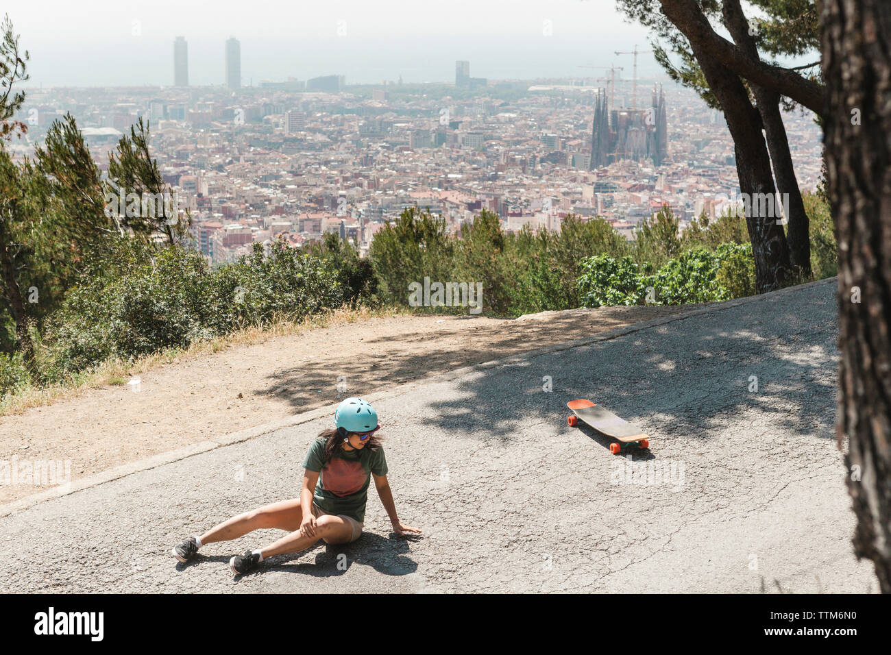 Portrait de femme tombant de skateboard sur route Banque D'Images