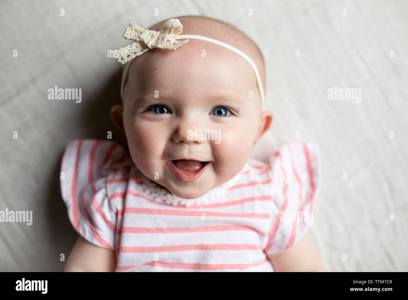 Close-up portrait of happy baby girl relaxing on bed at home Banque D'Images