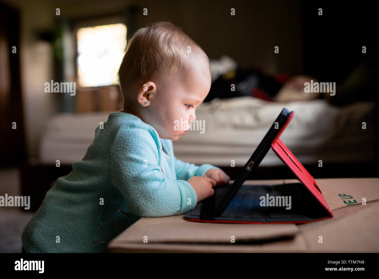 Baby Girl using tablet computer debout par fort à la maison Banque D'Images