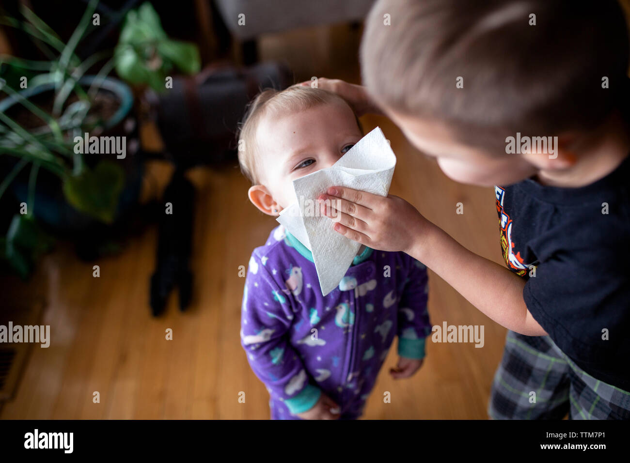 La peine d'essuyer le visage de soeur avec mouchoirs de papier à la maison Banque D'Images