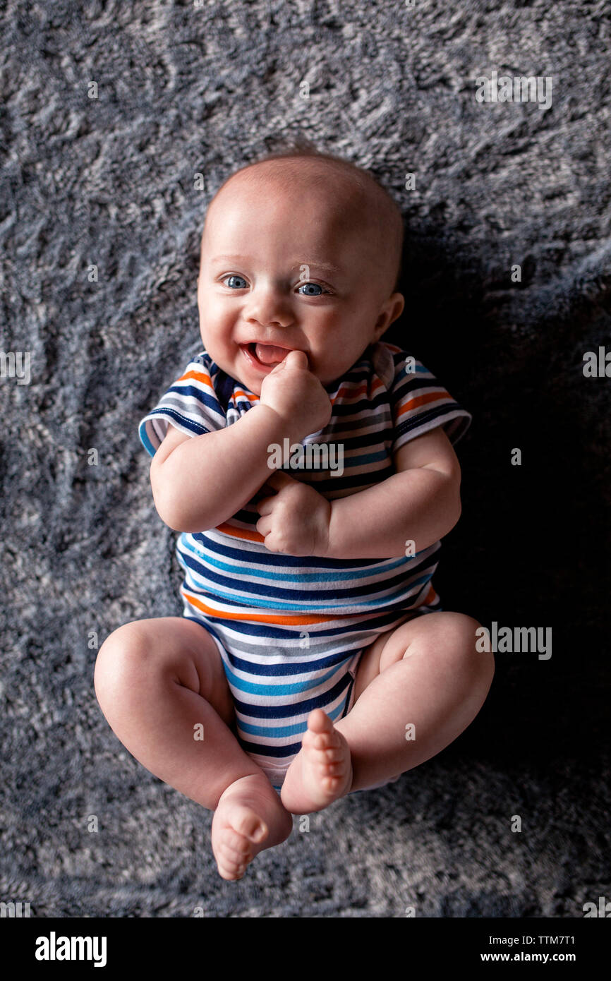 High angle portrait of happy baby boy lying on bed at home Banque D'Images