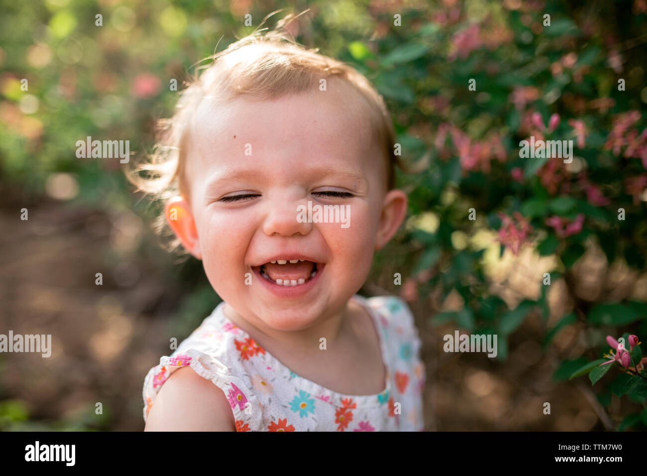 Close-up of baby girl standing against plants at park Banque D'Images