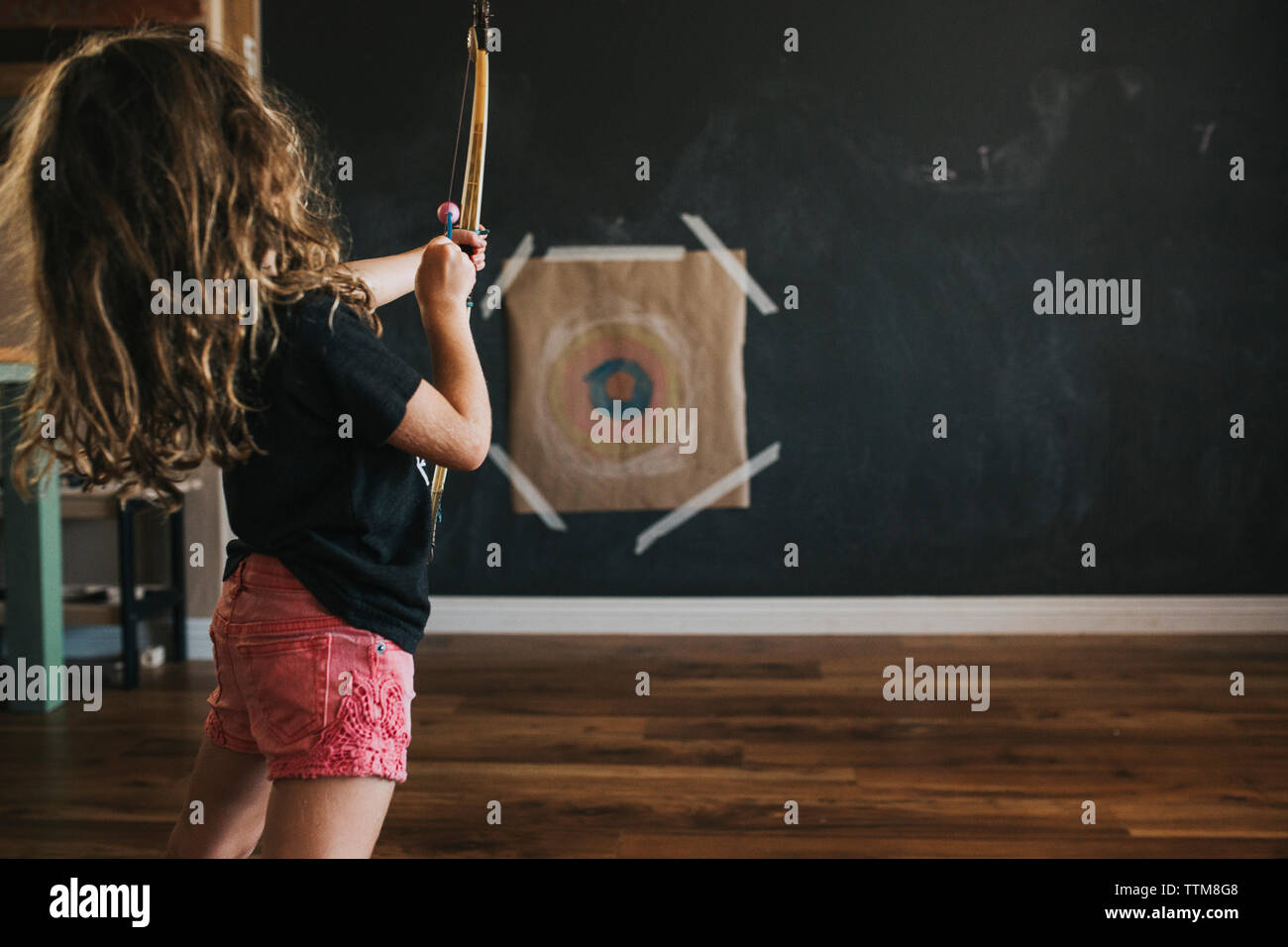 Vue latérale du girl flèche tout en visant l'article à la maison Banque D'Images