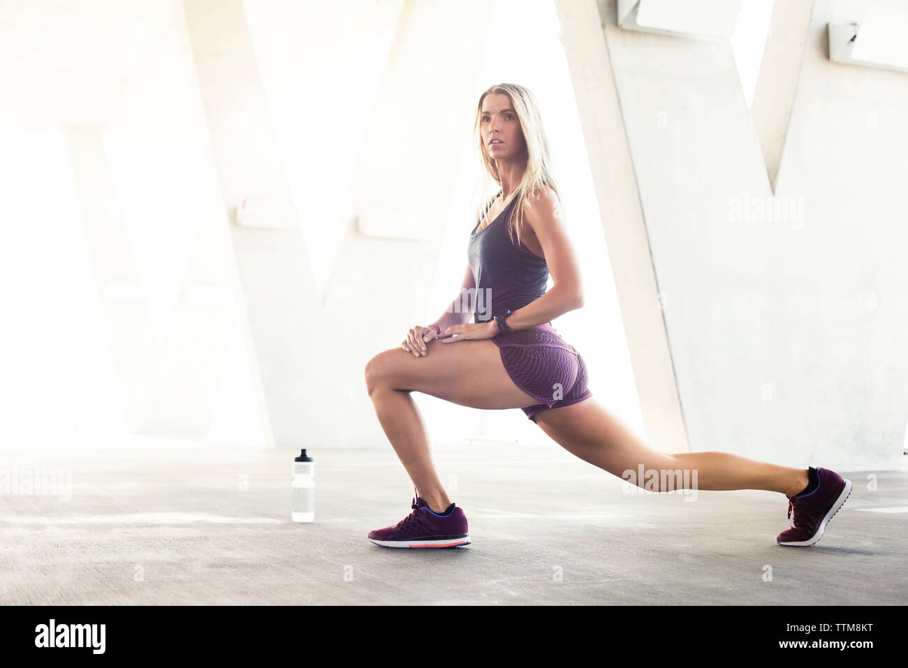 Vue latérale de l'athlète féminine confiant de faire des exercices d'étirement en stationnement Banque D'Images
