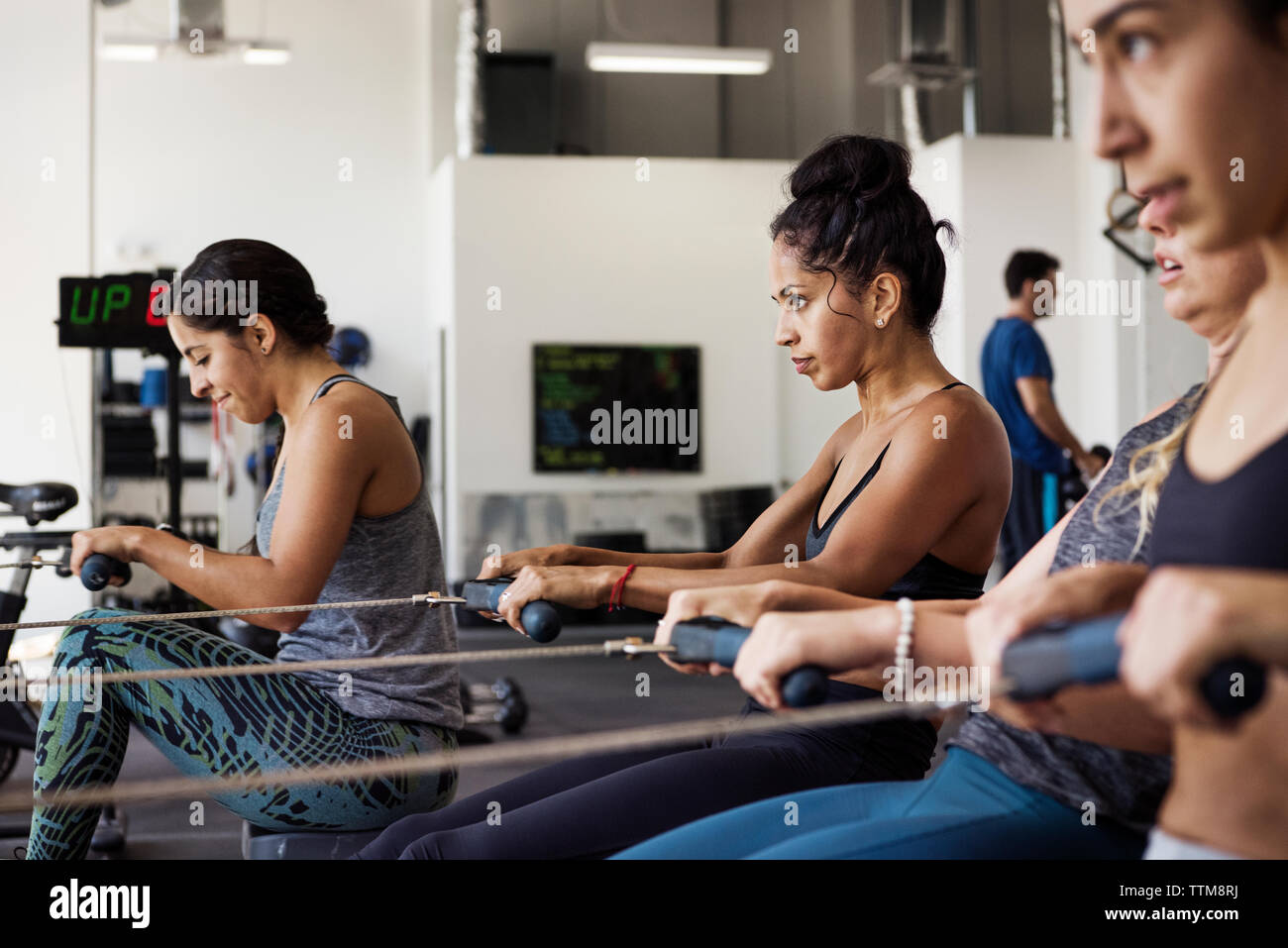 Les athlètes de sexe féminin déterminé l'exercice sur les machines à ramer en gym crossfit Banque D'Images