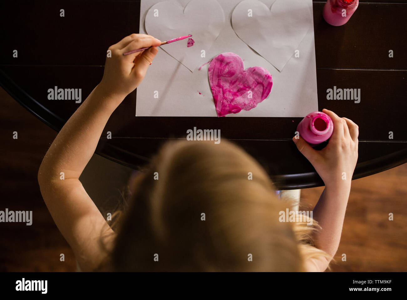 High angle view of girl coloring cœur des formes sur le tableau à la maison Banque D'Images