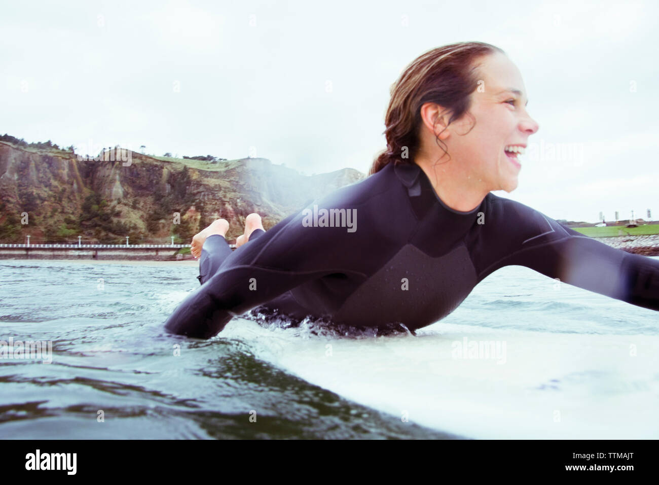 Happy woman lying on surf en mer contre sky Banque D'Images